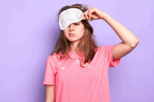 Woman groggily lifting a sleep mask from her face